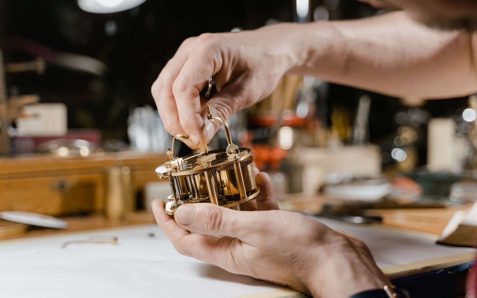 Adult hands holding a brass goniometer over a desk, the degree scale legible — close crop, upright format
