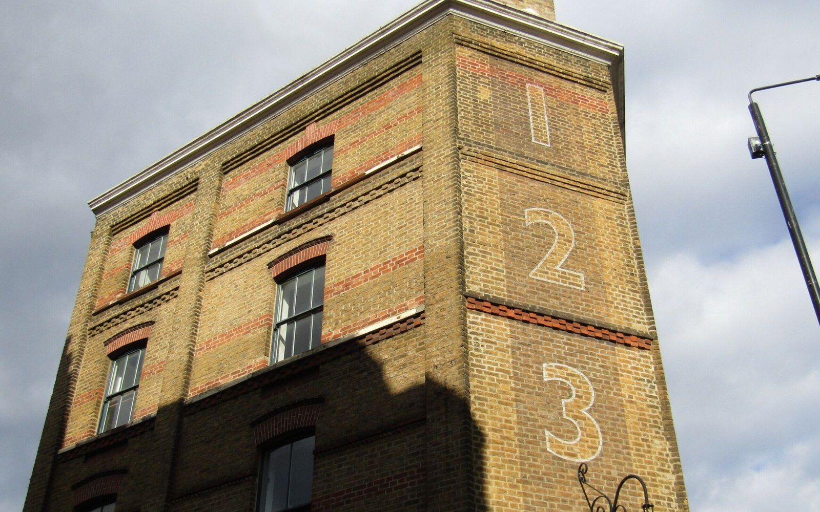 Corner of a brick building with numbers 1, 2, 3 painted vertically on the edge