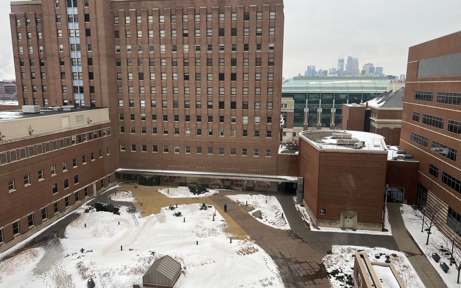 Snowy courtyard between University of Minnesota Health Sciences Center buildings with city skyline behind