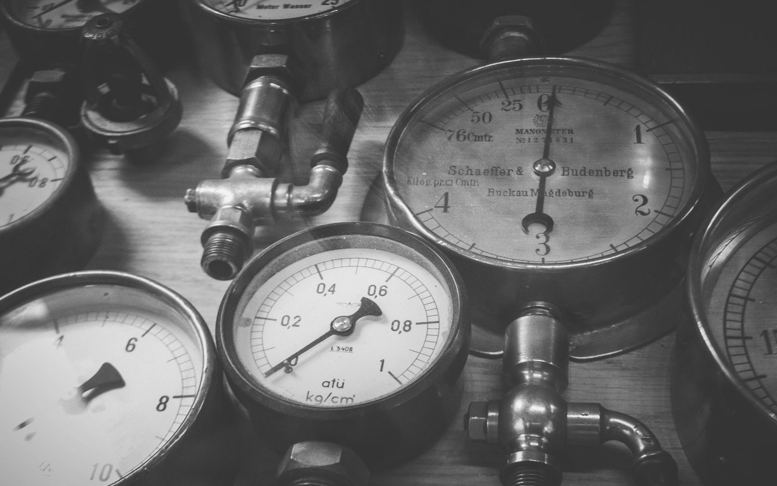 Vintage brass pressure gauges with brass fittings arranged on a wooden surface