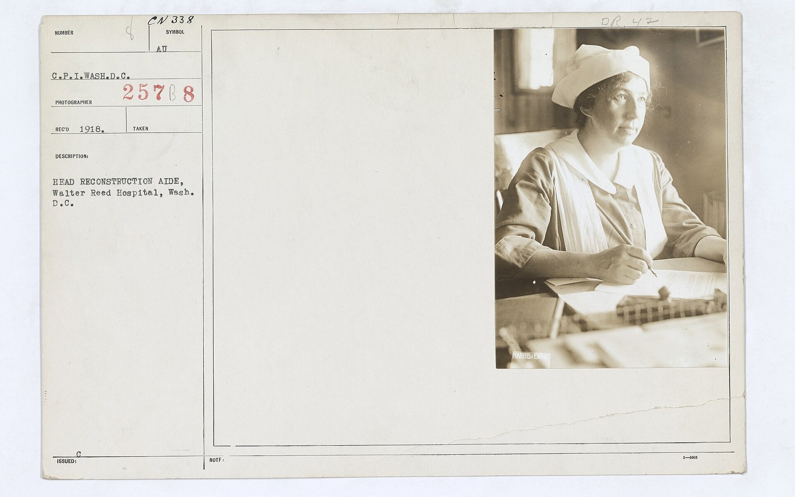 Head reconstruction aide seated at a desk writing in a ledger at Walter Reed Hospital