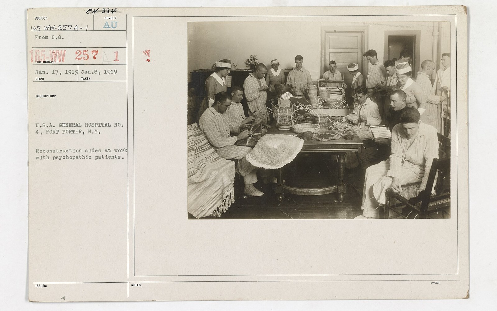 Patients gather around a table weaving baskets under staff supervision at a general hospital ward