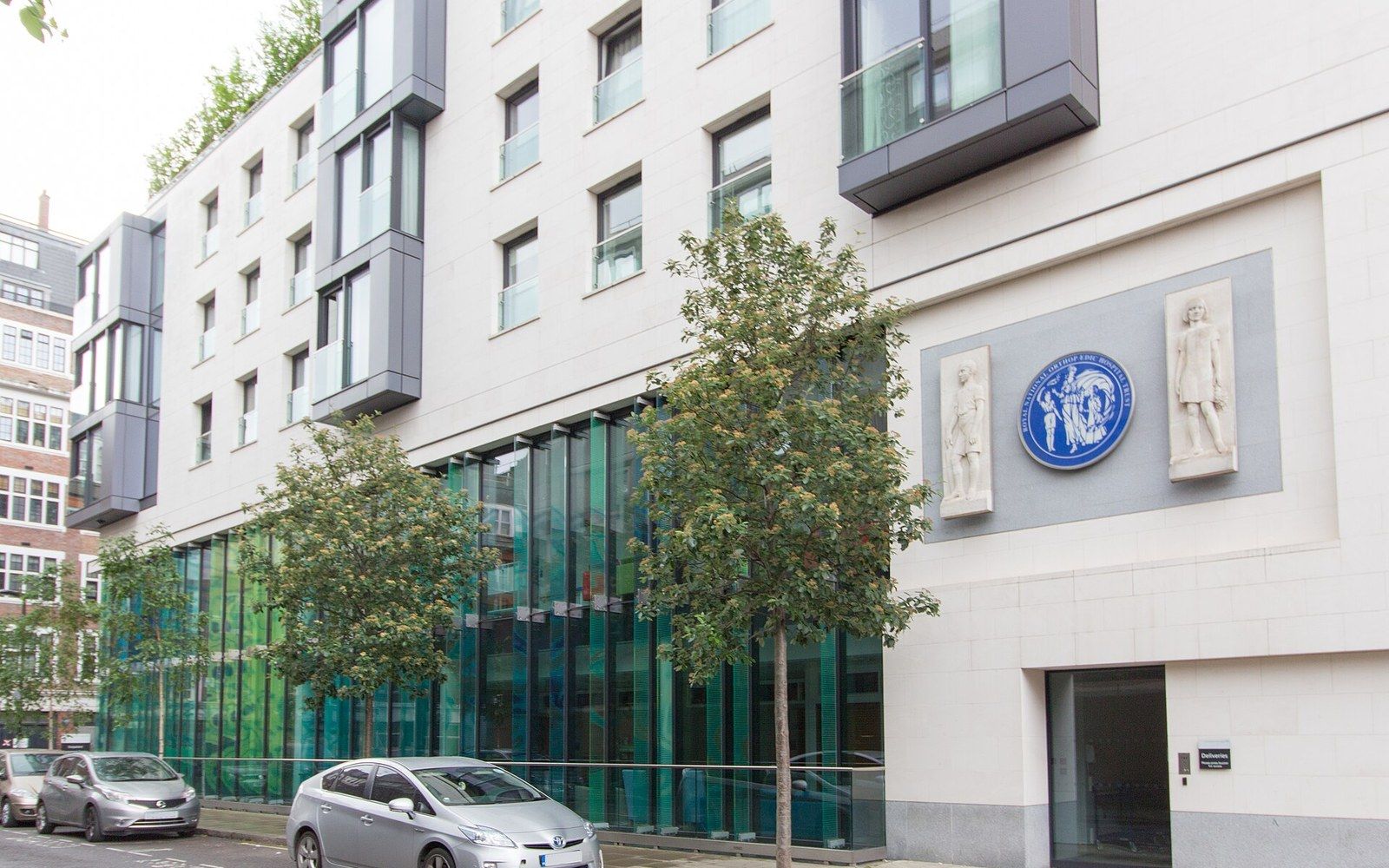 Modern building facade with a blue commemorative plaque flanked by carved stone figures