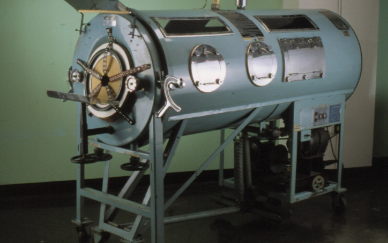An Emerson iron lung on display in a museum setting, the riveted steel cylinder at full length, no person inside — landscape